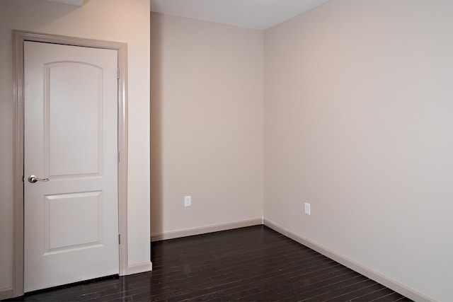 spare room with dark wood-style flooring and baseboards