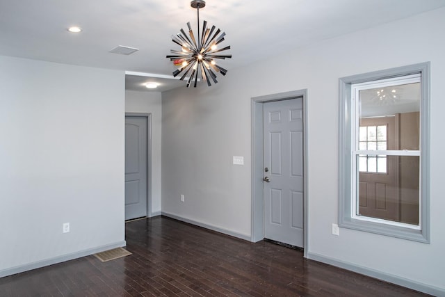 empty room featuring a chandelier, dark wood-style floors, baseboards, and recessed lighting