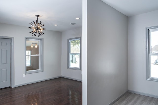 unfurnished room featuring a chandelier, wood finished floors, baseboards, and recessed lighting