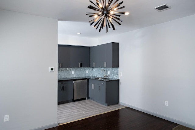 kitchen with dishwasher, a sink, light wood-style flooring, backsplash, and a chandelier