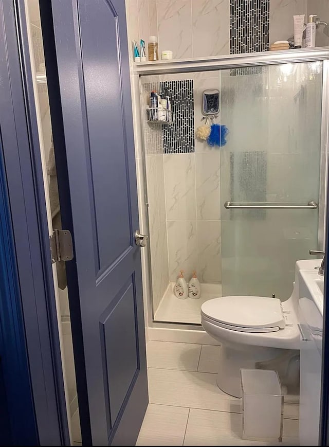 full bath featuring a stall shower, toilet, and tile patterned flooring