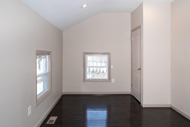 spare room with vaulted ceiling, dark wood-style floors, and baseboards