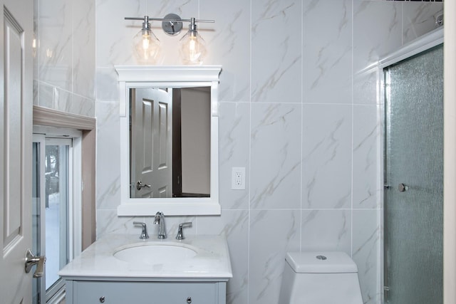 bathroom with tile walls, vanity, and toilet