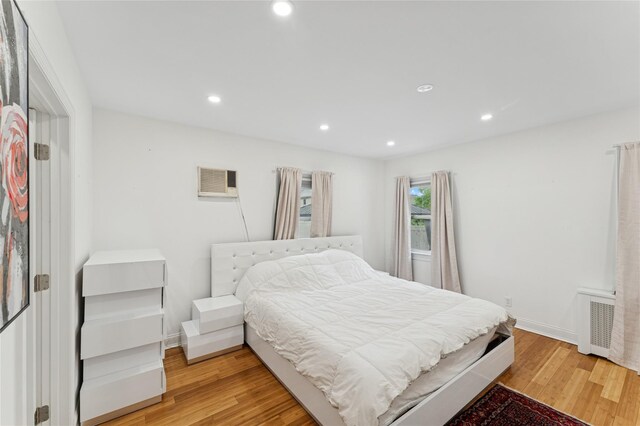 694 The Fenway, Baldwin, NY 11510 - bedroom featuring recessed lighting, radiator heating unit, light wood-style flooring, a wall mounted AC, and baseboards