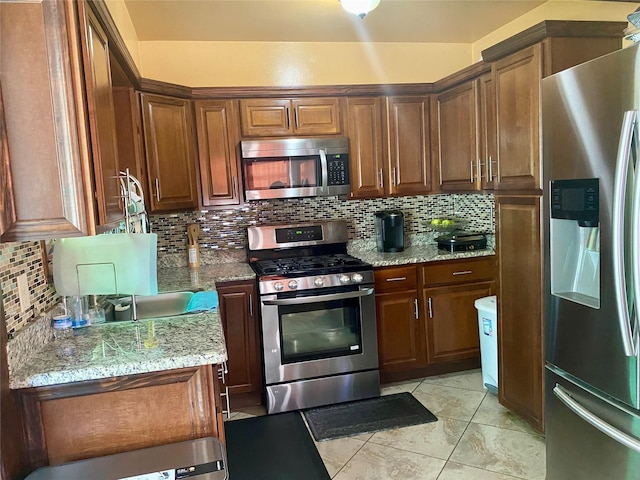 kitchen with stainless steel appliances, backsplash, and light stone counters