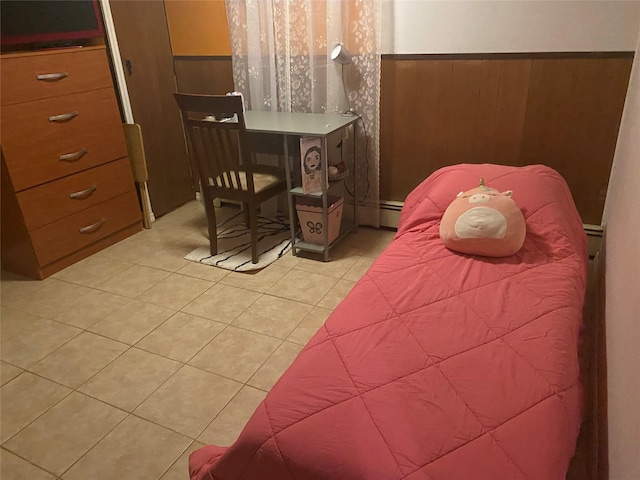 bedroom with wainscoting, light tile patterned floors, baseboard heating, and wood walls