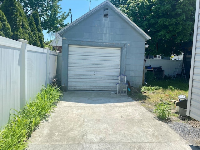 detached garage with concrete driveway and fence
