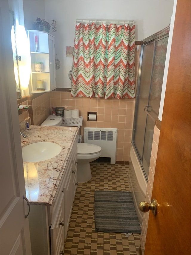 bathroom featuring radiator, toilet, vanity, tile walls, and tile patterned floors