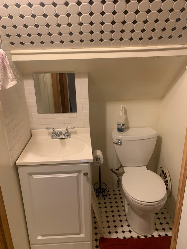 half bath featuring toilet, vanity, and tile patterned flooring