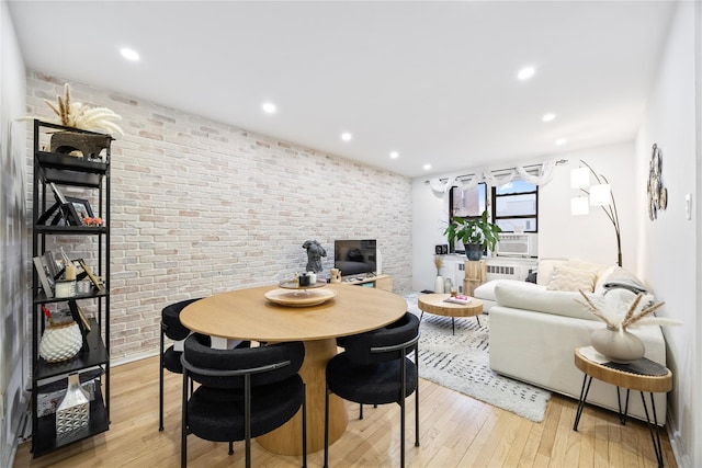 dining room with brick wall, light wood-style floors, recessed lighting, radiator heating unit, and cooling unit
