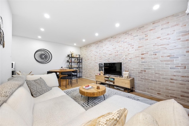 living room featuring wood finished floors, recessed lighting, and brick wall