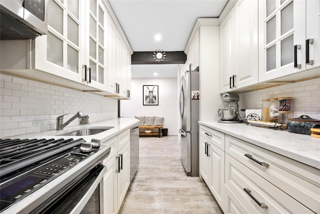 kitchen with appliances with stainless steel finishes, backsplash, a sink, white cabinets, and recessed lighting