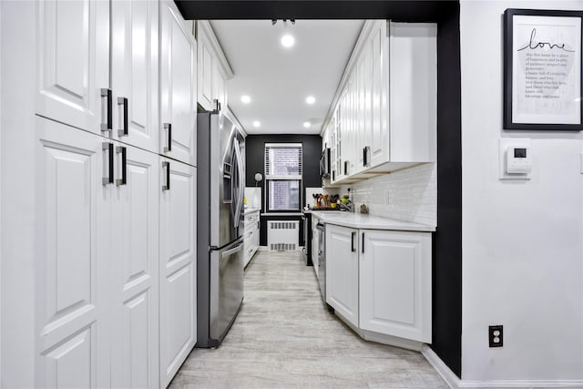 kitchen featuring stainless steel appliances, radiator heating unit, white cabinetry, and recessed lighting