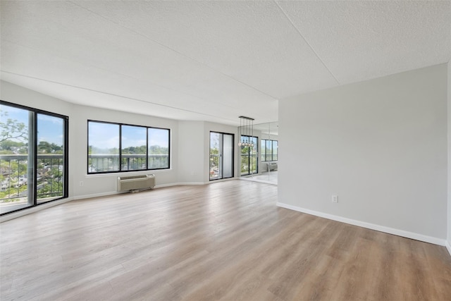 400 High Point Dr Unit 313, Hartsdale, NY 10530 - spare room with light wood-style floors, a wall unit AC, a textured ceiling, and baseboards