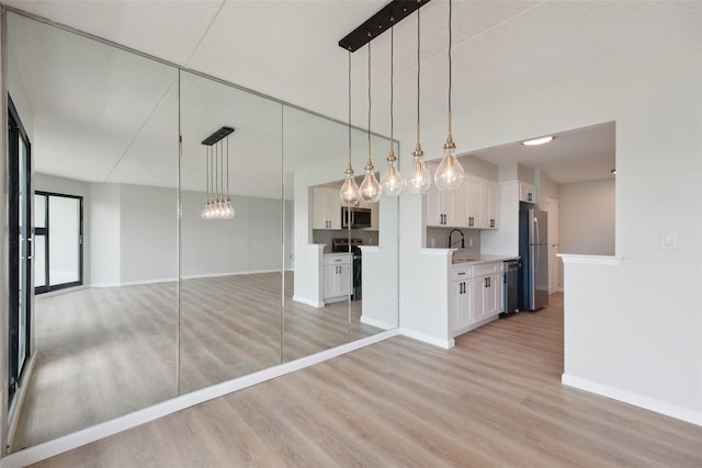 400 High Point Dr Unit 313, Hartsdale, NY 10530 - kitchen featuring open floor plan, stainless steel appliances, light wood-type flooring, white cabinets, and baseboards