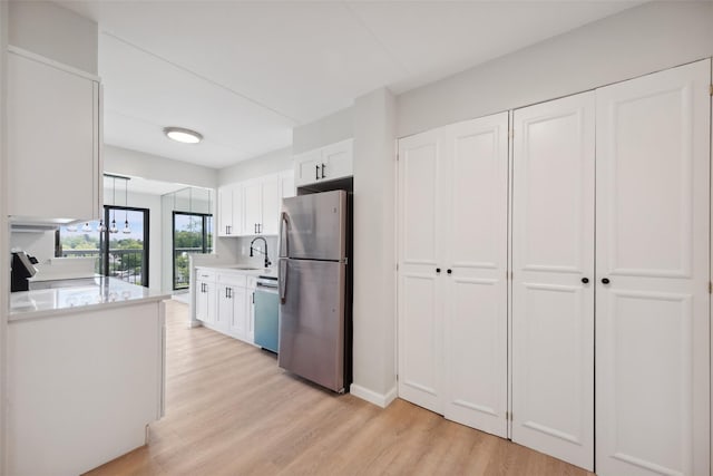 400 High Point Dr Unit 313, Hartsdale, NY 10530 - kitchen featuring stainless steel appliances, a sink, light countertops, white cabinets, and light wood-style floors