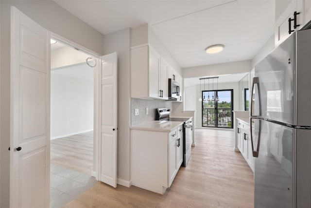 400 High Point Dr Unit 313, Hartsdale, NY 10530 - kitchen featuring appliances with stainless steel finishes, light countertops, white cabinets, light wood finished floors, and tasteful backsplash