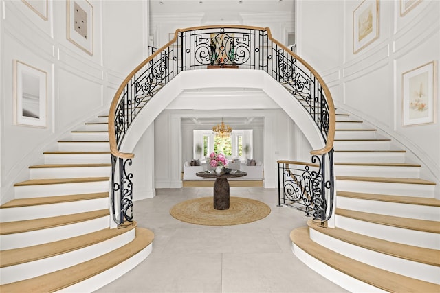 7 Beverly Rd, Kensington, NY 11021 - tiled foyer featuring stairs, a decorative wall, a towering ceiling, a chandelier, and ornamental molding