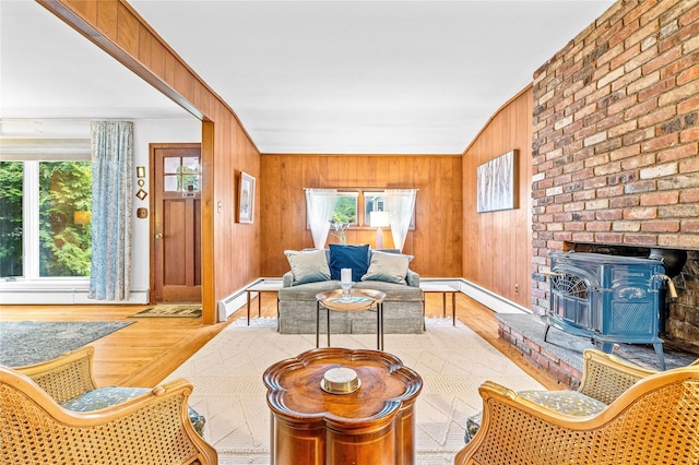 63 Lexington Dr, Croton-On-Hudson, NY 10520 - living room featuring wood finished floors, healthy amount of natural light, a wood stove, wooden walls, and baseboard heating