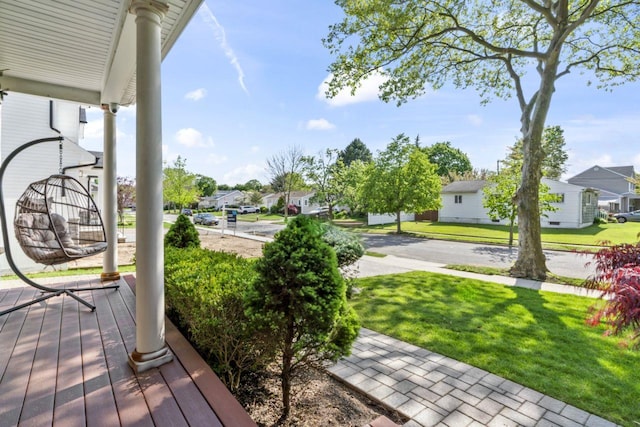 wooden terrace with a residential view, a porch, and a lawn