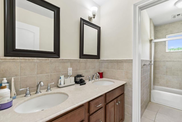 full bath featuring tile walls, double vanity,  shower combination, wainscoting, and tile patterned floors