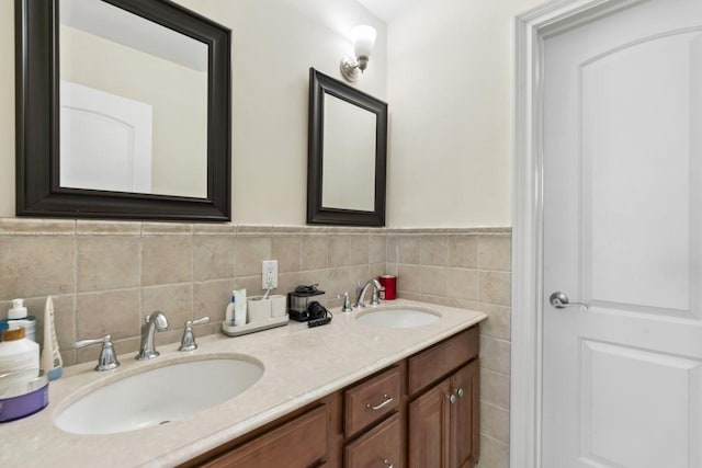 full bath with double vanity, tile walls, and a wainscoted wall