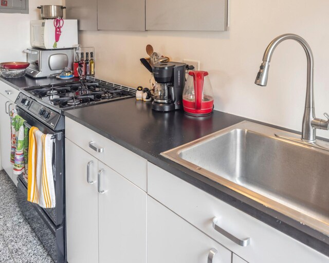 160 Cabrini Blvd Unit 62, New York Manhattan, NY 10033 - kitchen featuring gas range oven, a sink, dark countertops, and white cabinetry