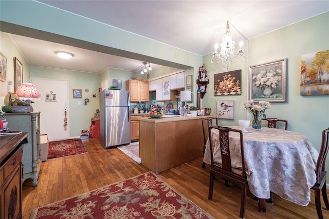 100 S Ocean Ave Unit 2E, Freeport, NY 11520 - kitchen featuring freestanding refrigerator, a peninsula, wood finished floors, a chandelier, and light brown cabinetry