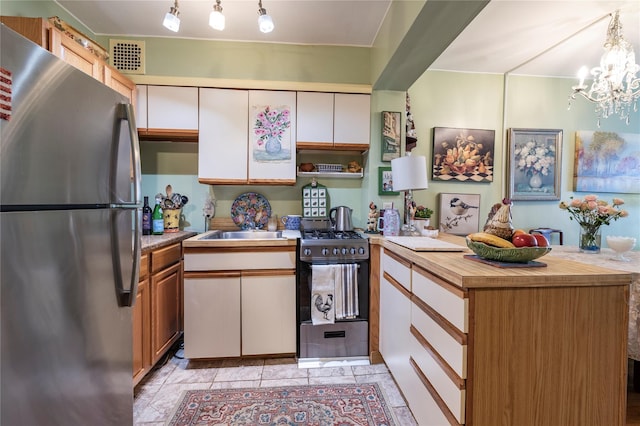 100 S Ocean Ave Unit 2E, Freeport, NY 11520 - kitchen featuring stainless steel appliances, a peninsula, a chandelier, wooden counters, and white cabinetry