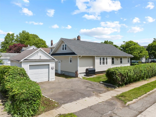 175 N Columbus Ave, Freeport, NY 11520 - view of front facade with driveway, an outdoor structure, and a chimney