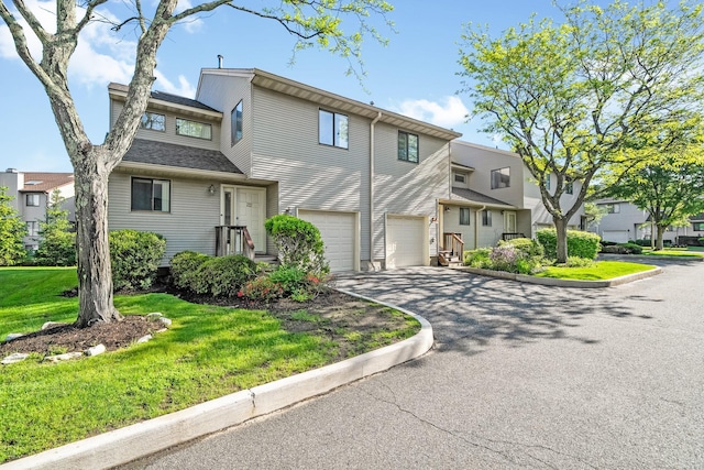 view of front of house with driveway, an attached garage, a front yard, and a residential view