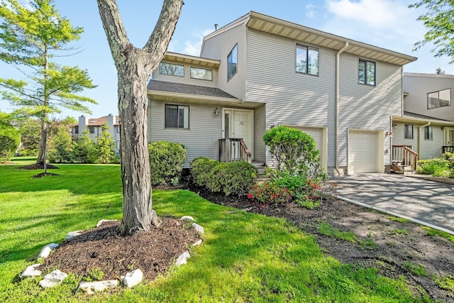 view of property with an attached garage, driveway, and a front yard