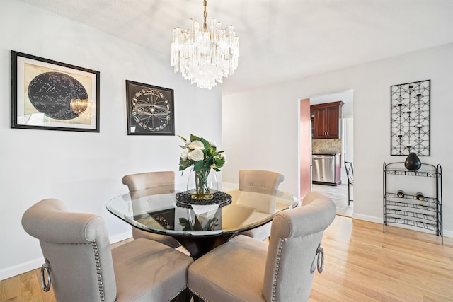 dining space featuring a chandelier, baseboards, and light wood-style flooring
