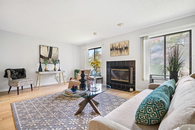 living area with a tiled fireplace, wood finished floors, and baseboards