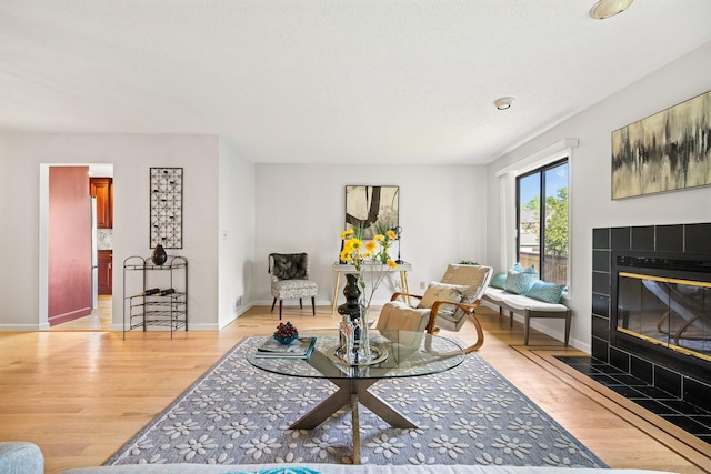 living area with a fireplace, light wood-style floors, and baseboards