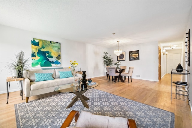 living area featuring a chandelier, light wood-style flooring, and baseboards