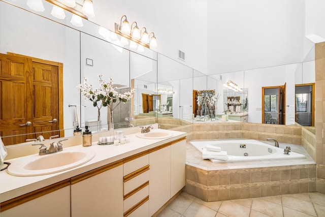 bathroom with a high ceiling, tile patterned floors, a whirlpool tub, and double vanity