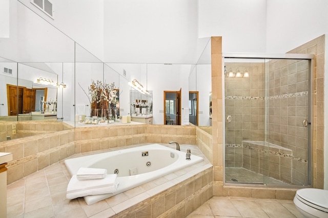 full bath featuring a towering ceiling, a shower stall, a tub with jets, tile patterned flooring, and toilet