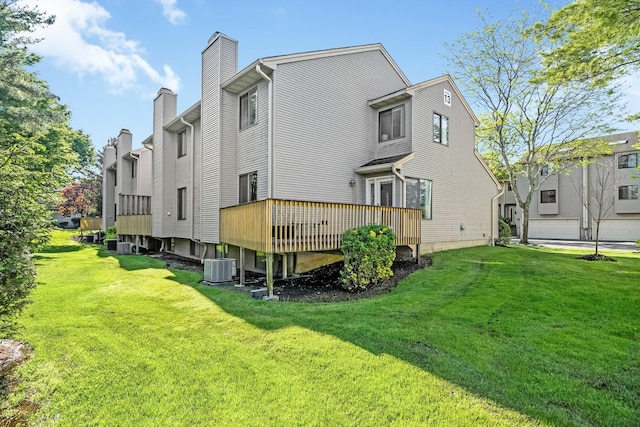 rear view of property featuring a lawn, a wooden deck, a chimney, and central air condition unit