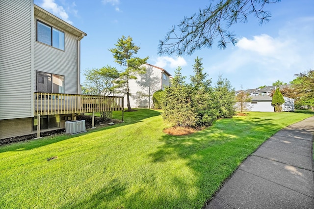 view of green lawn featuring a deck and central AC