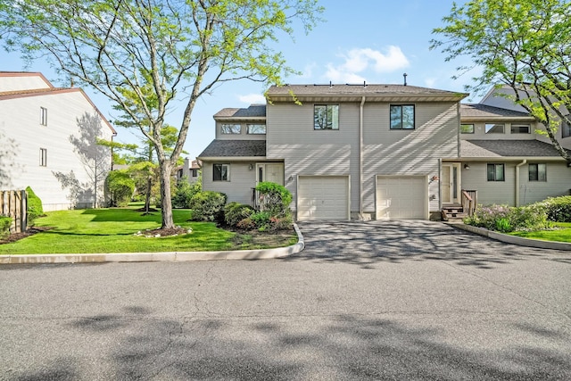 view of front facade with asphalt driveway, an attached garage, and a front yard