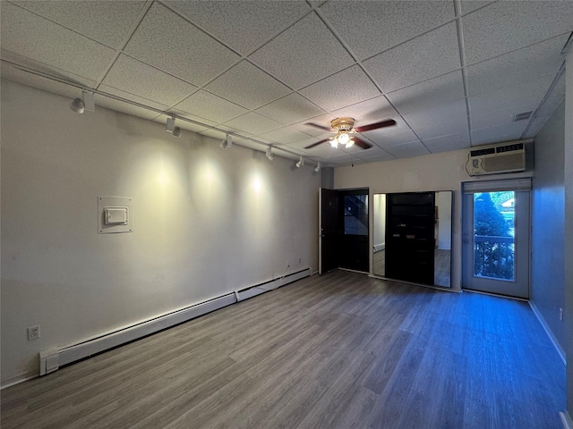 spare room featuring baseboard heating, rail lighting, wood finished floors, baseboards, and ceiling fan