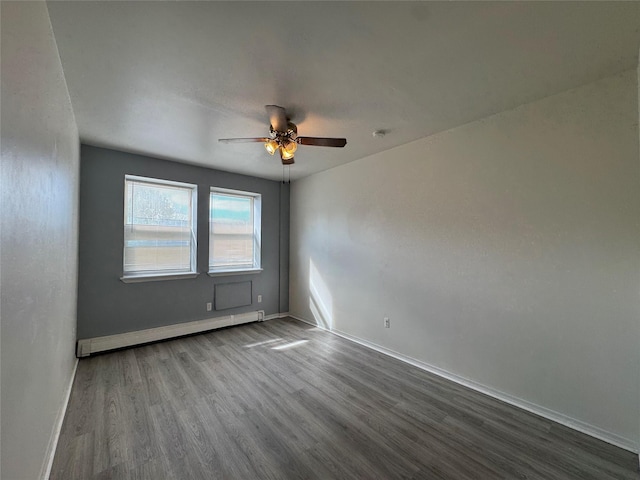 unfurnished room with baseboard heating, dark wood-style floors, a ceiling fan, and baseboards