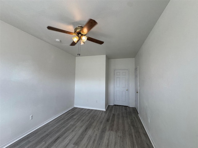 empty room featuring a ceiling fan, dark wood-type flooring, baseboards, and a smoke detector