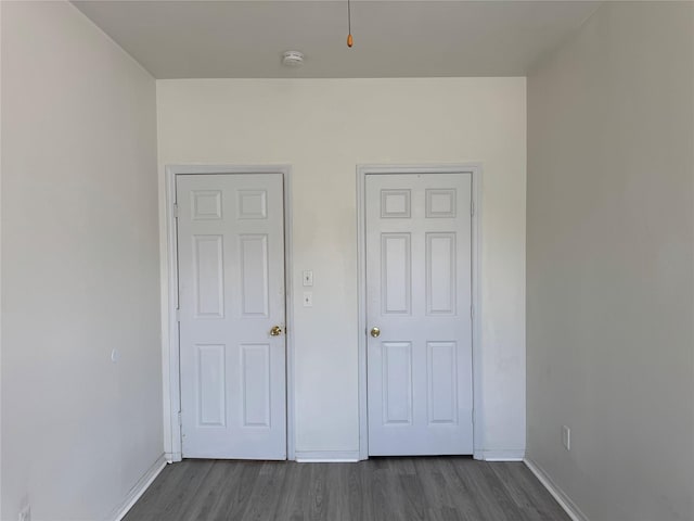unfurnished bedroom with dark wood finished floors and baseboards