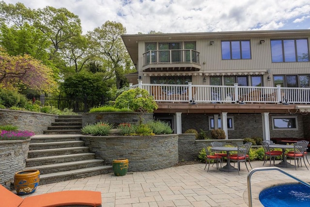 rear view of house with stairs, a patio, and a balcony