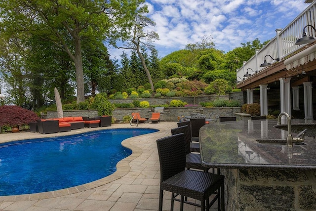 outdoor pool with outdoor lounge area, a sink, a patio area, and outdoor dining space
