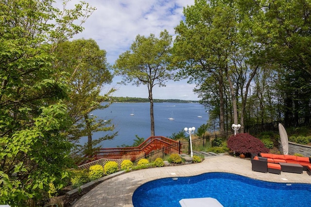 view of pool with a water view, a patio area, an outdoor living space, and fence