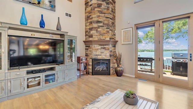 12 Sunset Path, Port Jefferson, NY 11777 - living room with wood finished floors, a fireplace, a water view, a towering ceiling, and baseboards