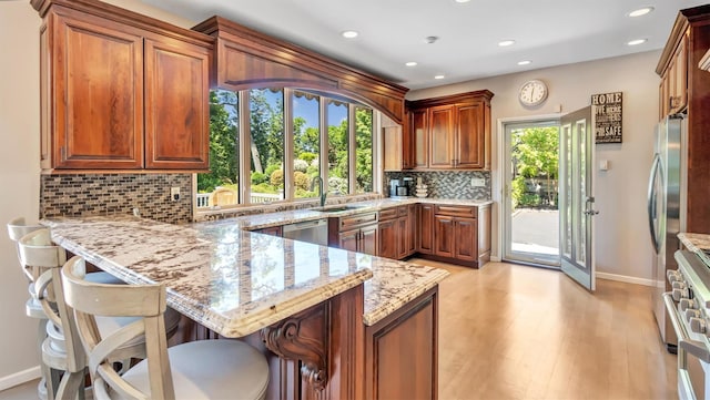 12 Sunset Path, Port Jefferson, NY 11777 - kitchen featuring baseboards, appliances with stainless steel finishes, a peninsula, light stone counters, and tasteful backsplash